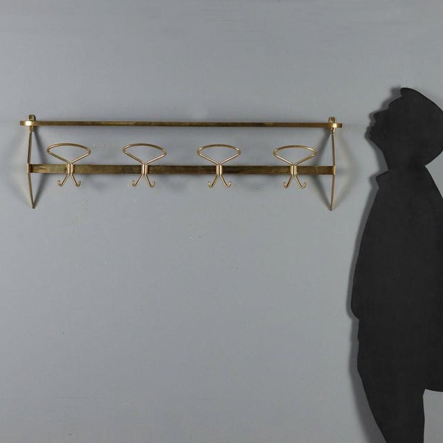 Wall mounted coat rack with brass hat rack. This piece is attributed to the mentioned designer/maker. It has no...
