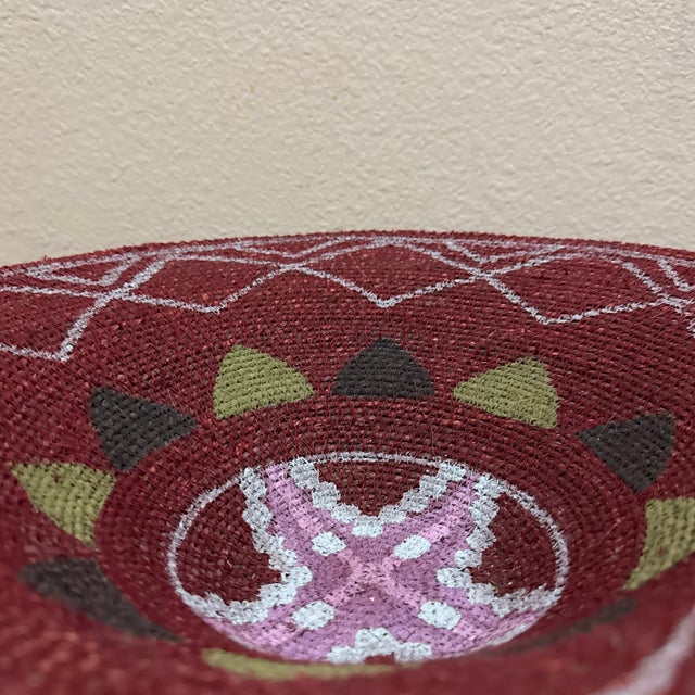 Add a touch of warmth and artisanal charm to your space with this beautifully handwoven maroon basket. Featuring an eye-...