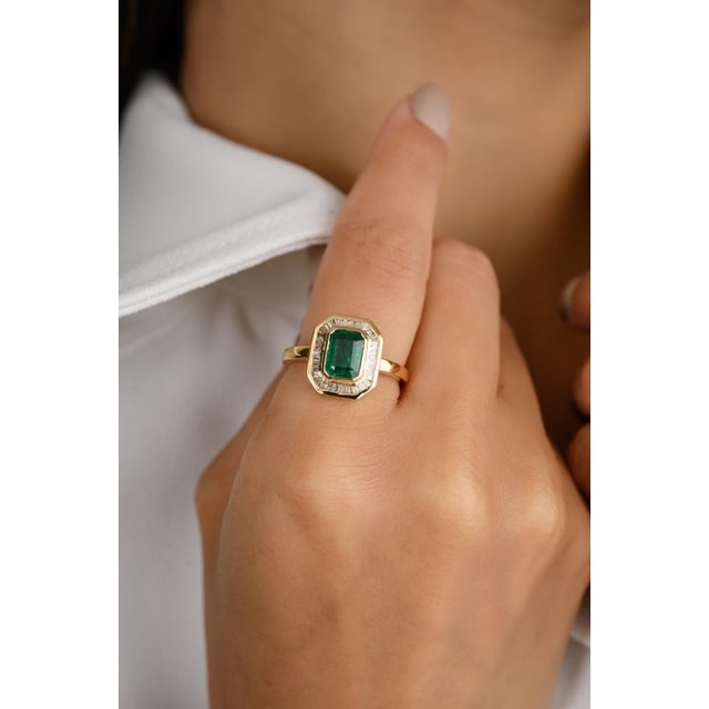 This 18k gold statement ring showcases an octagon-cut center emerald, surrounded by a dazzling baguette-cut diamond halo....