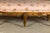 A French Louis XV style wooden footstool from the 19th century with six carved cabriole legs and upholstery. Indulge in...