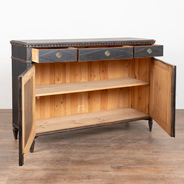 Swedish Gustavian black painted pine sideboard or console with upper carved dentil molding and three upper drawers over...
