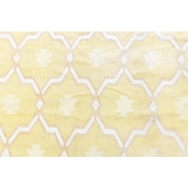 This striking 1940s Indian Dhurrie rug radiates warmth and cheer with its sunny buttery yellow and soft cream palette,...