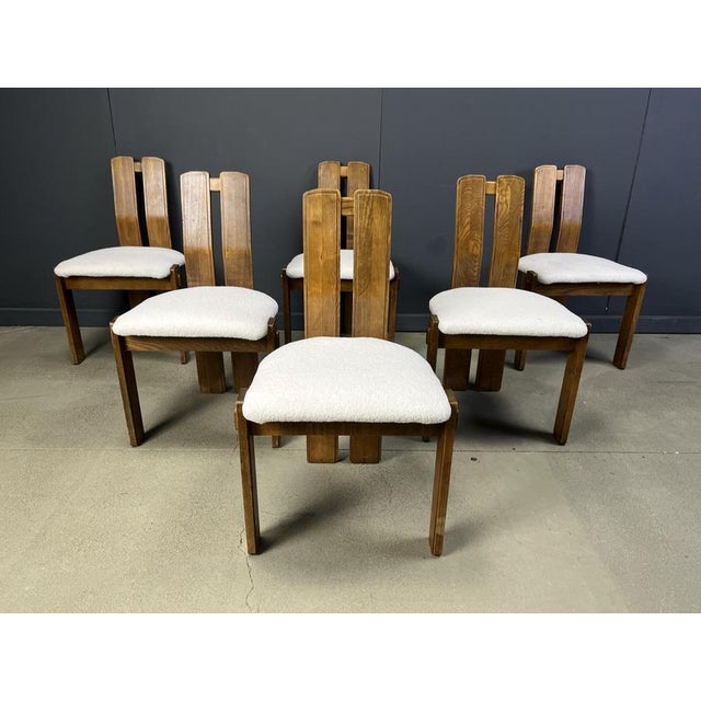 Robust brutalist dining chairs with solid wooden frames and newly upholstered seats in a fresh and cosy boucle fabric....