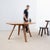 Large round table with a 1970s design, made of solid pear wood. It features a wide circular top composed of several broad...