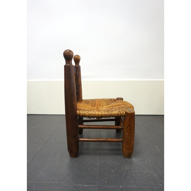 Low fireplace chair in solid wood with a rush seat. A mid-20th-century French handcrafted piece in the style of French...