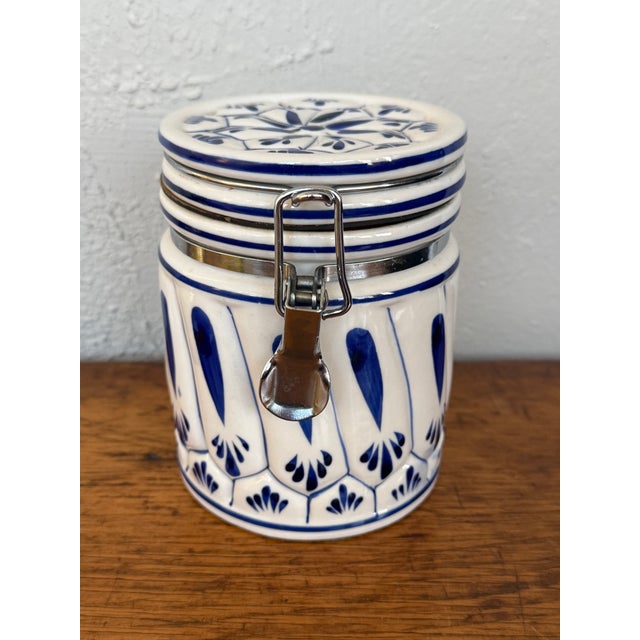 Ceramic kitchen canister hand painted in cobalt blue on a white glaze in a Delft style. A flower medallion decorates the...