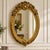Elegant French-style oval wall mirror featuring a richly hand-carved frame with intricate ornamental detailing and a...