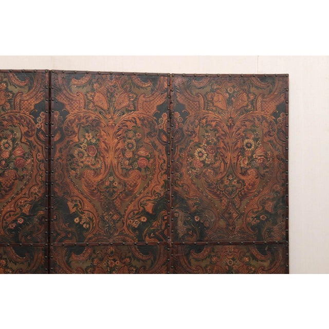 A large-sized Italian embossed and painted leather room divider, with nail head trim accents, from the mid 20th century....