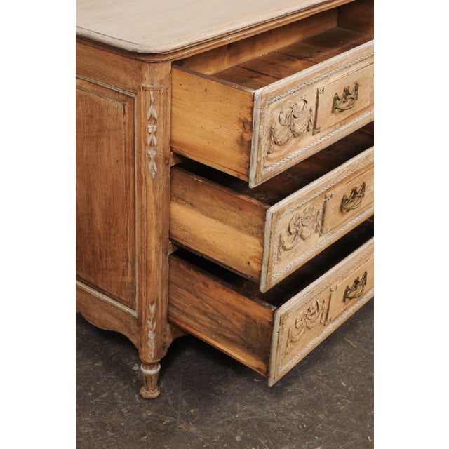 A French carved wood chest of three drawers from the early 19th century. This antique commode from France features a...