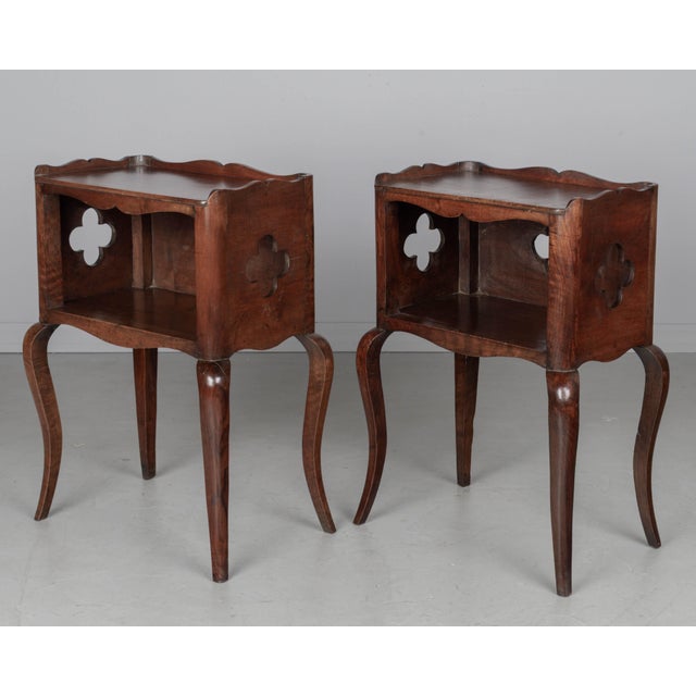 A pair of Louis XV style Country French side tables or nightstands made of solid walnut, with open niche and pierced...