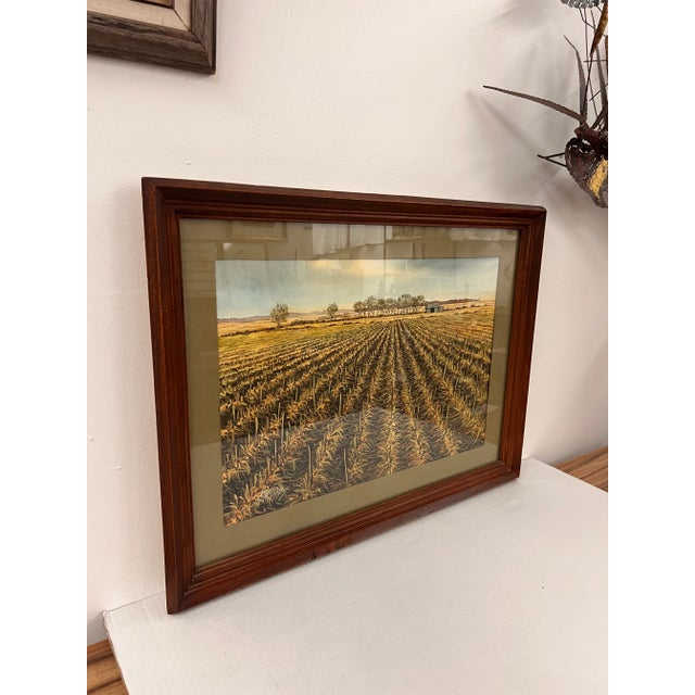 The watercolor painting depicts a serene agricultural landscape with neatly arranged rows of crops extending toward the...