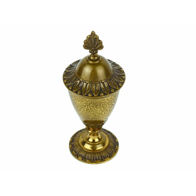 Add timeless elegance to your space with this vintage bronze urn, featuring a sculptural leaf-shaped finial and embossed...