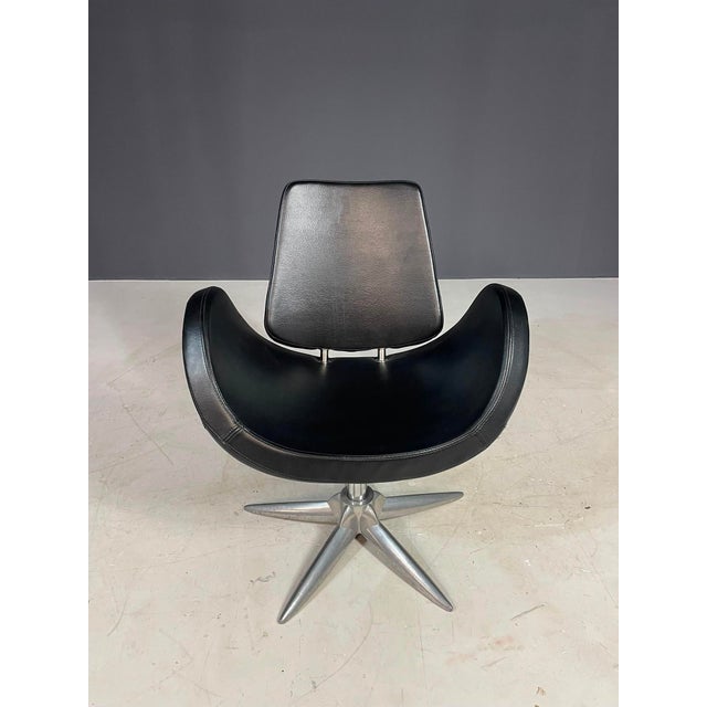 This vintage swivel chair features a distinctive sculptural silhouette, combining a curved black seat shell with a...