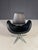 This vintage swivel chair features a distinctive sculptural silhouette, combining a curved black seat shell with a...
