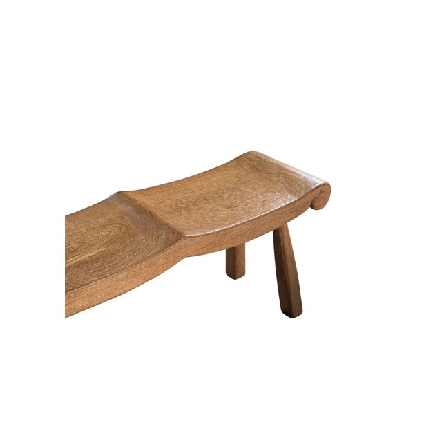 This three-seater solid teak bench is a striking example of sculptural craftsmanship and organic design. Defined by its...