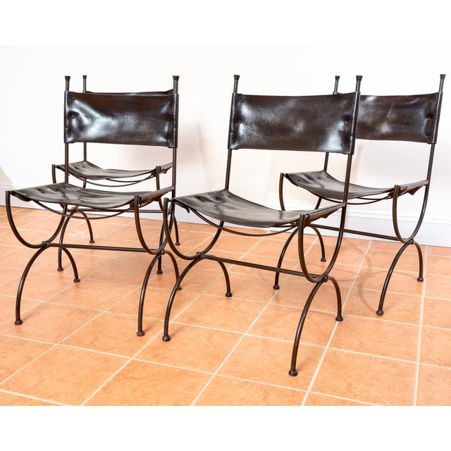 An impressive and rare set of four forged wrought iron and saddle leather dining chairs in lovely vintage condition....