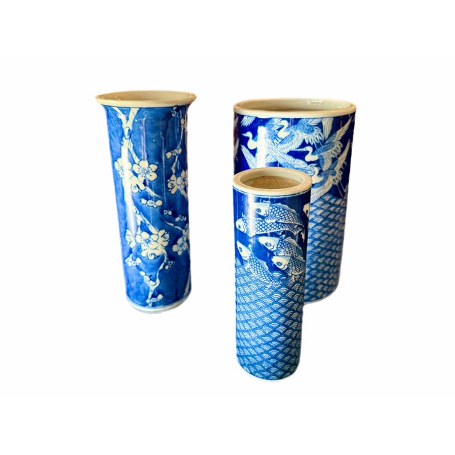 A complementary trio of Asian vases in blue and white. The smallest vase is decorated with a fan design motif and fish....