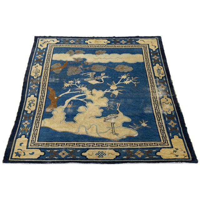 This striking antique Chinese Peking rug features a rich, vibrant indigo blue field adorned with classic pictorial motifs,...
