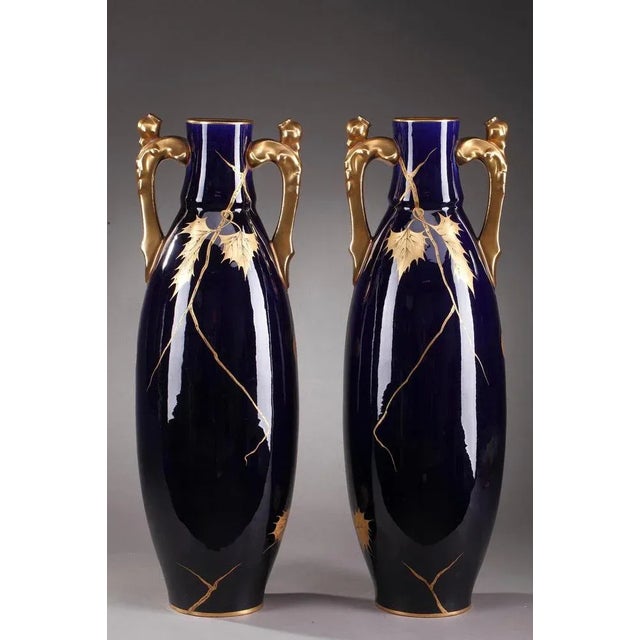 Large porcelain vases crafted by gustave asch in the late 19th century. Each vase is highlighted with cascading chestnut...