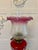 An antique Victorian brass oil lamp with cranberry glass font, raised on a finely cast Corinthian column with fluted stem...