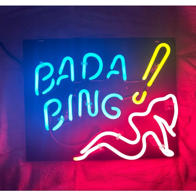 Bring the ultimate piece of cinematic TV history into your space with this authentic, vintage-style "Bada Bing" glass neon...