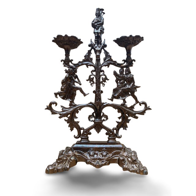 A substantial patinated cast iron candelabra with two lights, resting on a rocaille-decorated base. The central shaft,...