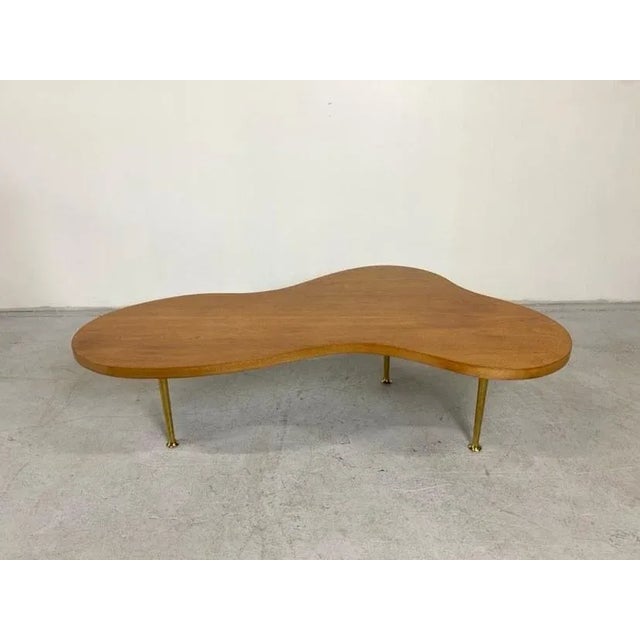 Stunning maple and brass biomorphic "cloud" coffee table by T.H. Robsjohn-Gibbings. It's simplicity and beauty speaks for...