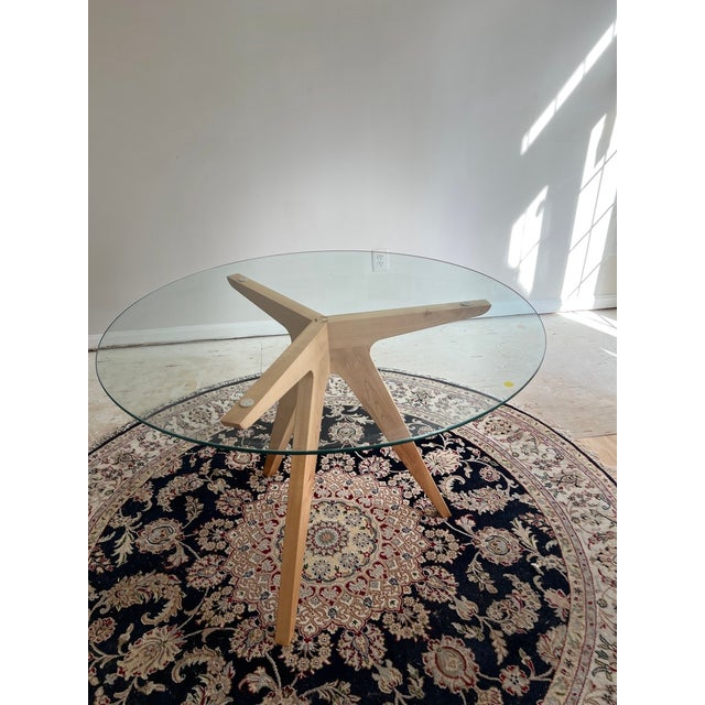 A beautifully crafted custom-made round glass table featuring a striking sculptural solid wood starburst base. The clean,...