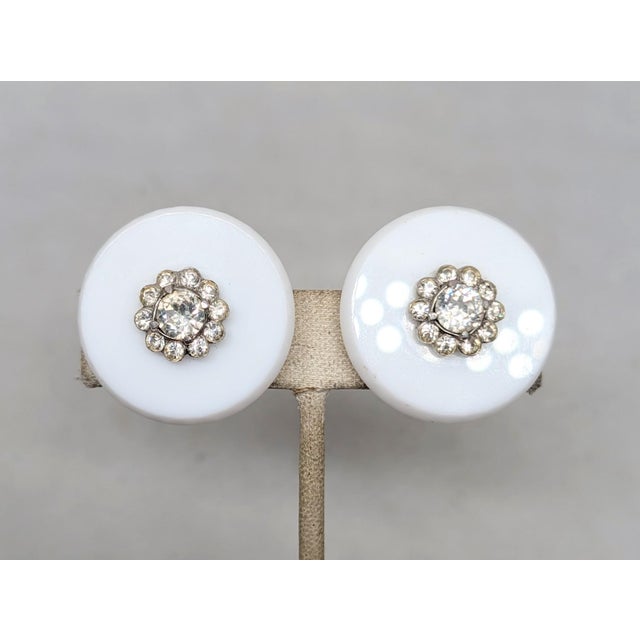 1960s round resin with round clear rhinestones in the center clip earrings. Marked "CASTLECLIFF" on the clips. Measure: 1...