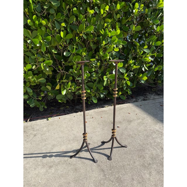 Striking pair of tall vintage iron candlesticks with sculptural forms, slender stems, stacked ring details, and...