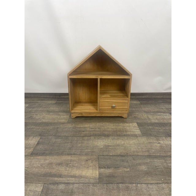 Indian rosewood bookcase with a drawer. A small, wooden bookcase in the shape of a house, crafted from warm-toned wood. It...