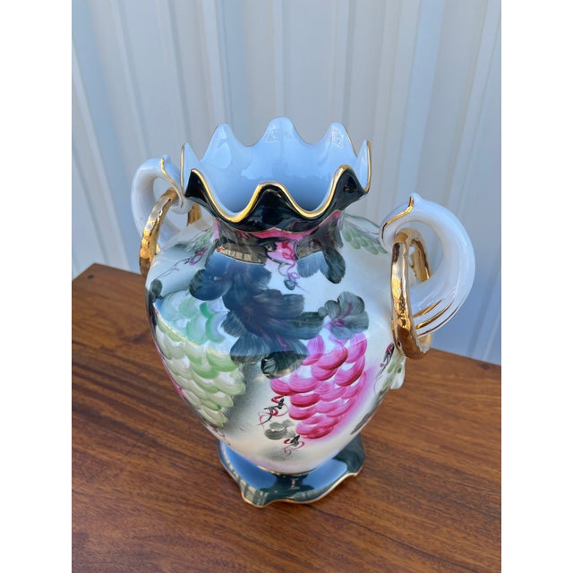 A stunning hand painted porcelain Nippon vase. Adorned with golden accents on a unique clam-shell rim and vase handles,...