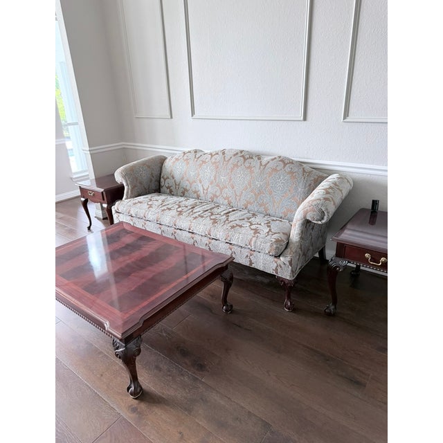 Elegant dark mahogany coffee table with a beautifully inlaid wood veneer top and classic ball-and-claw feet on all four...