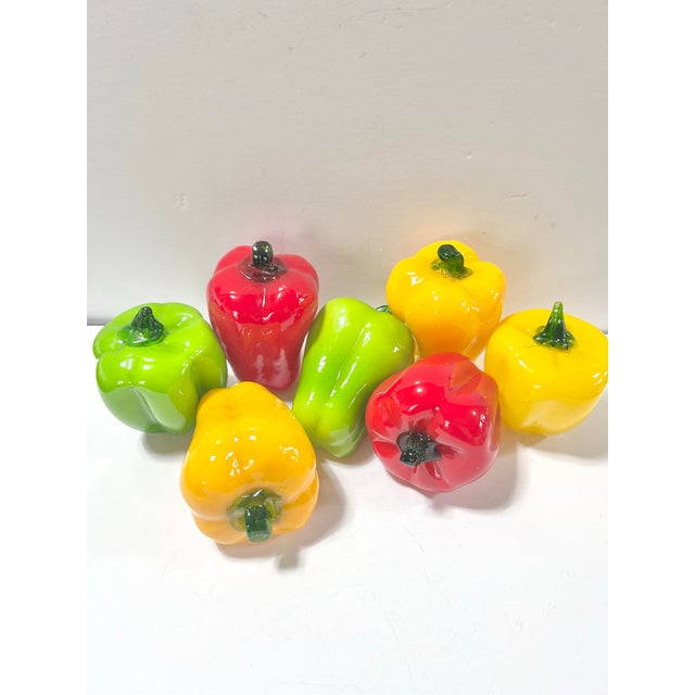 A vibrant set of vintage Murano-style blown art glass bell peppers in bright red, yellow, and green with applied green...