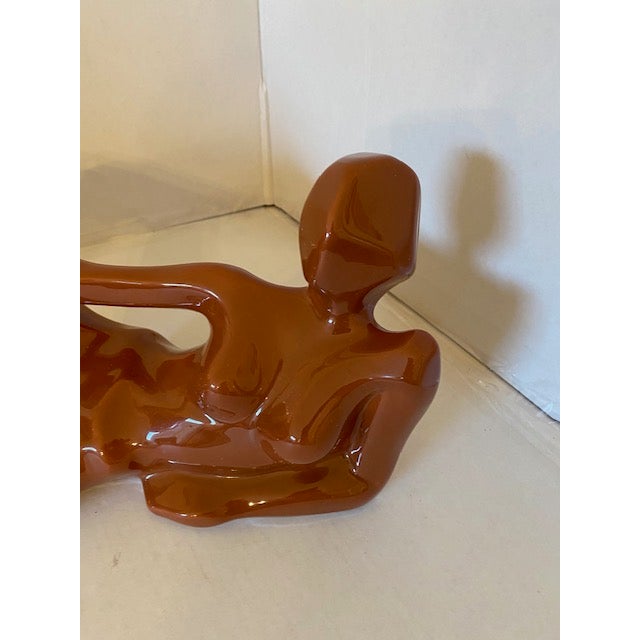 The piece is coated in a brilliant, high-gloss burnt orange ceramic glaze that beautifully accentuates its dramatic...