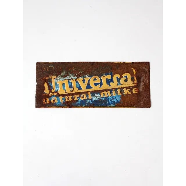 A vintage "Universal Natural Milker" metal sign. With lots of character, the aged metal sign features the embossed company...