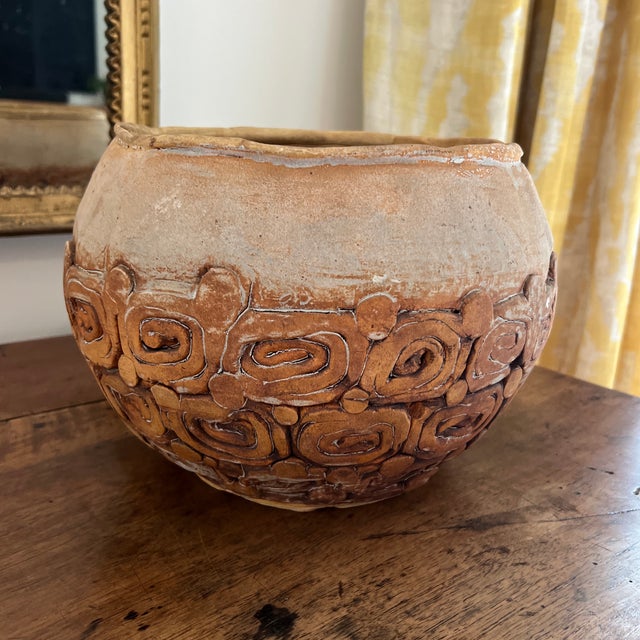handmade ceramic pot with an earthy, textured finish and spiral-patterned embellishments along the lower half. A unique...