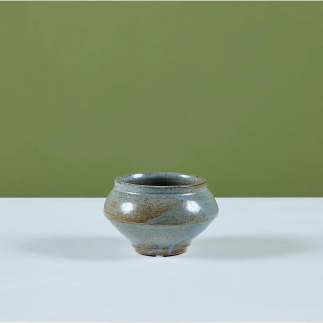 A studio ceramic bowl, by American ceramicist, Warren MacKenzie. The bowl features a blue speckle glaze that tapers at the...