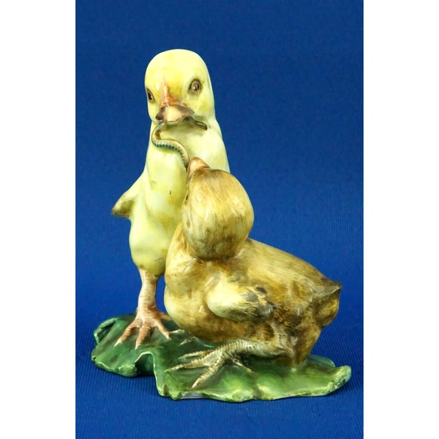 Ceramic sculpture depicting a pair of chicks with a worm, numbered in green under the base with a catalog number. We...