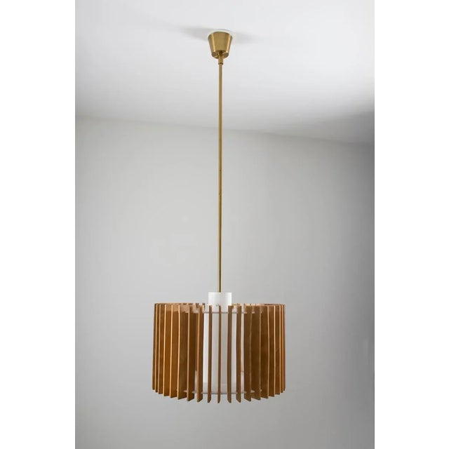 This adjustable pendant was designed by Hans-Agne Jakobsson and is made of brass, glass, wood, and plastic. It features...