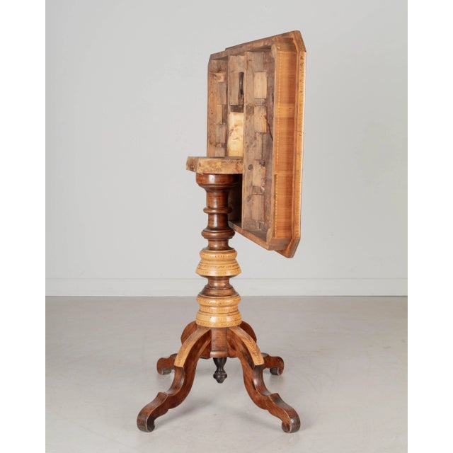 A 19th Century Italian marquetry tilt-top center table made of solid walnut with inlaid veneers of walnut and various...