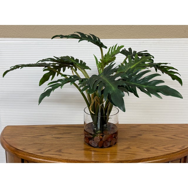 Design Plus Gallery presents an Artificial Philodendron Xanadu in a Clear Glass Vase. Deeply lobed green leaves extend...
