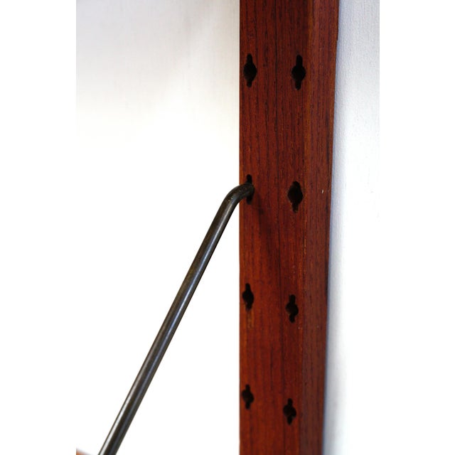 Teak wall system of Danish origin. The shelves are extra wide, measuring 100 cm. Using brass rods, they can be hung in the...