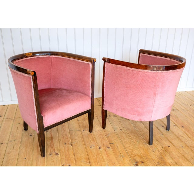 A rare and exceedingly charming pair of Edwardian Art Nouveau mahogany inlaid armchairs in lovely antique condition. Made...