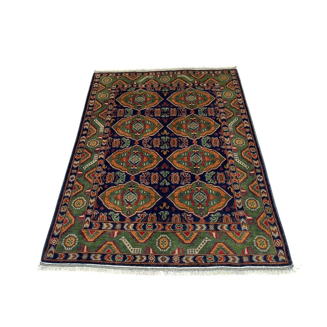 Eight green geometric medallions stand out against the deep navy field of this wool rug. Layered tribal borders repeat the...