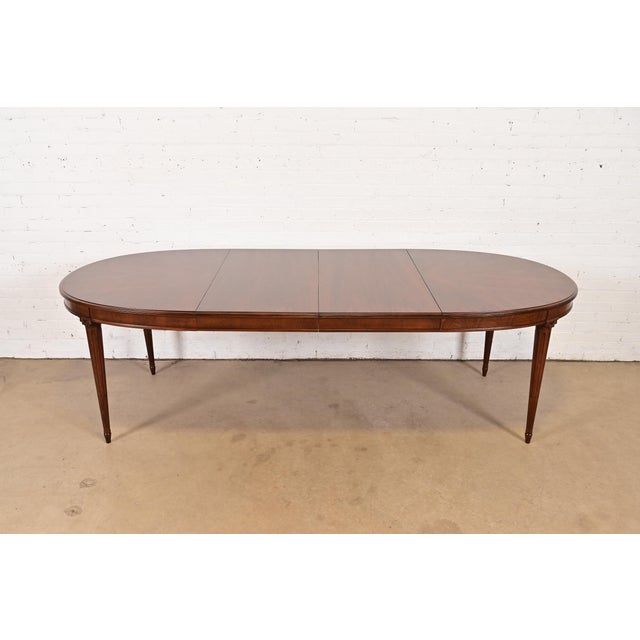 An exceptional French Regency Louis XVI style extension dining table By Henredon USA, Circa 1960s Carved walnut, with...