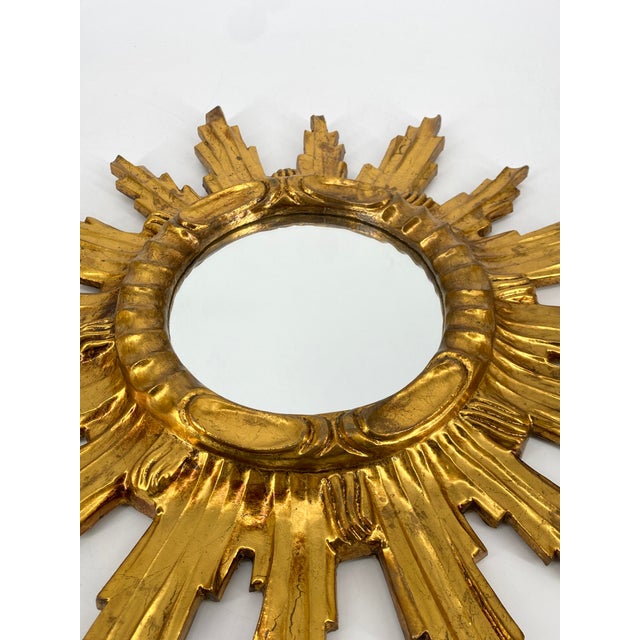 * Sun-shaped * Round mirrors in the center * with a decorated ring directly around the mirrors * Made of wood * Gold-...