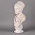This plaster bust depicts a woman in the classical manner, her hair drawn back beneath a wrapped fillet into a high coiled...