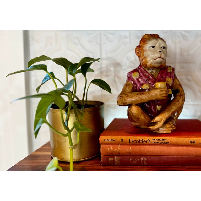 Charming vintage ceramic monkey figurine depicted seated and smoking a corn cob–style pipe. This whimsical piece features...