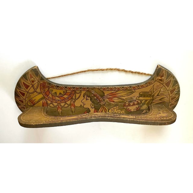 Early 1900s pyrography canoe shaped tie holder with Indian maiden graphics. Tie holder has wear, discolorations, paint loss.